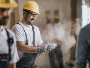 Happy construction worker with dusty gloves